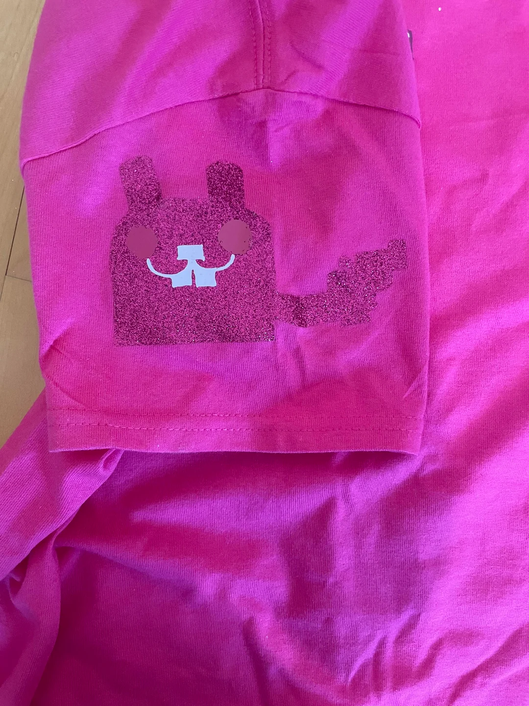Image of the left sleeve of the shirt. Has a pink glittery version of the rabbit with matte eyes and mouth.